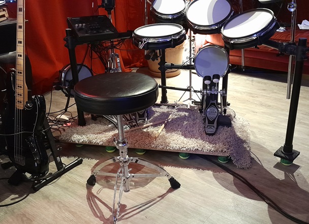 vue d'ensemble de la batterie, posée sur l'estrade, elle-même posée sur des balles de tennis coincées dans des boîtes de dérivation électriques.